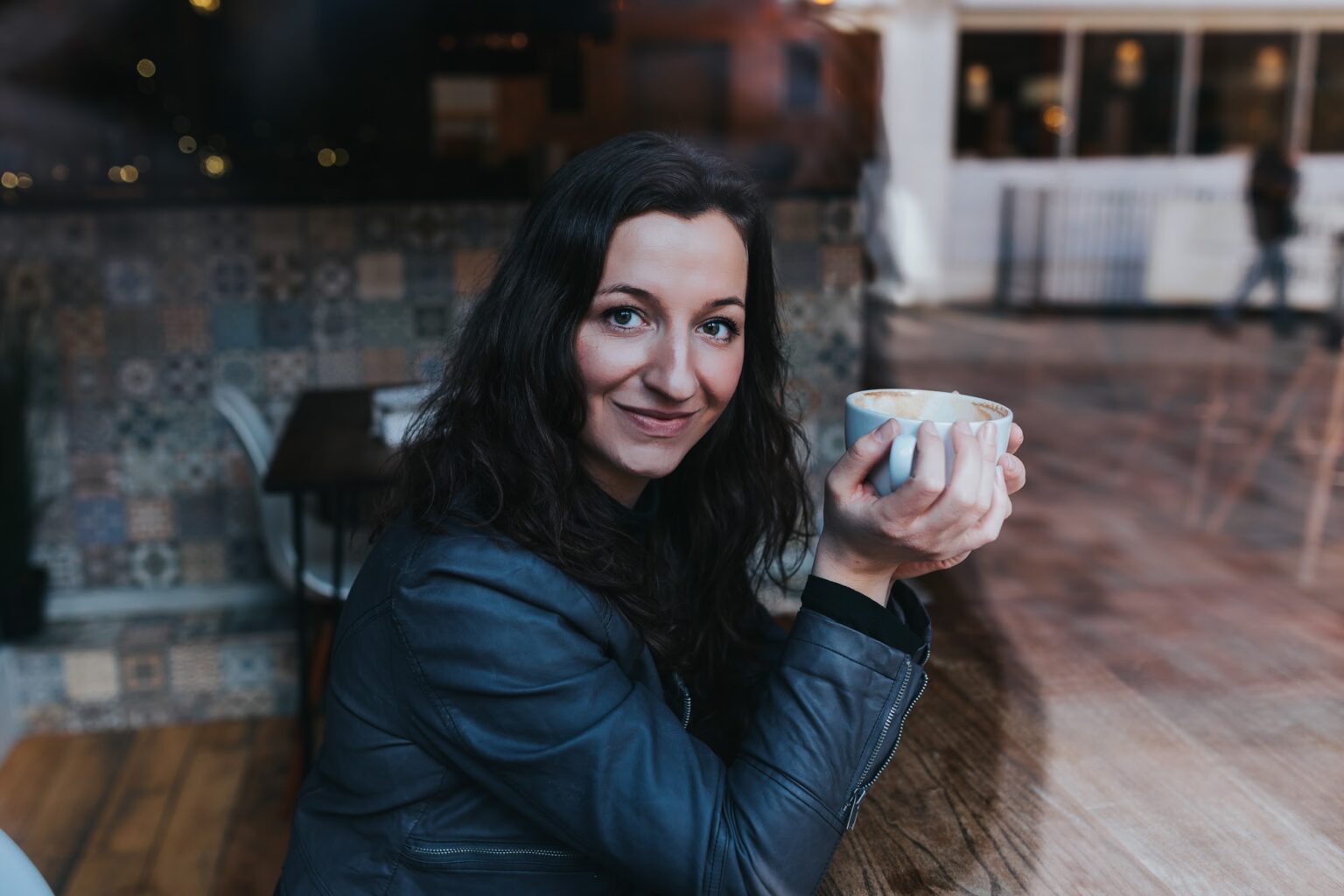 Rebecca Lockwood smiling, holding a coffee in a café